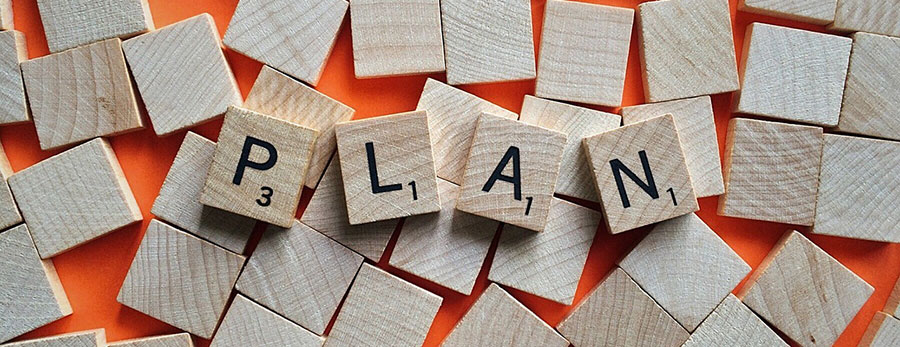 Scrabble-like board game tiles spelling out the word "Plan"