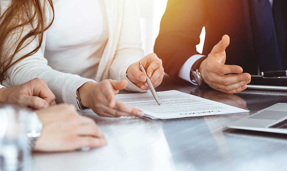 Business people discussing contract while working together in sunny modern office. Unknown businessman and woman with colleagues or lawyers at meeting